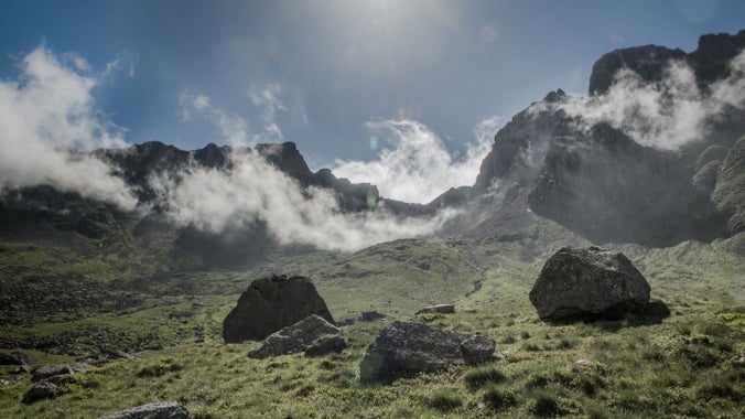 View of Scafell Pike from Hollow Stones in Wasdale, Cumbria. White mist sits on the fell with blue skies in the background.